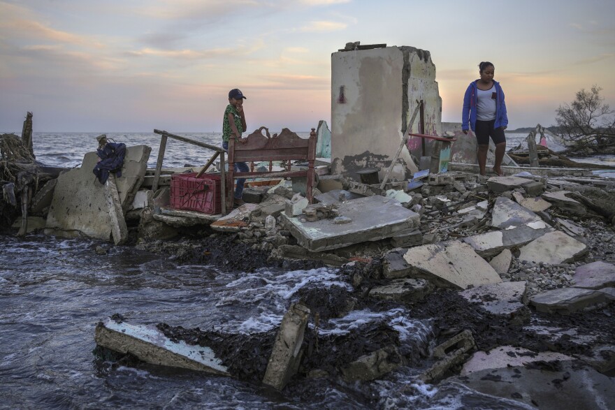 Yahir Mayoral and Emily Camacho walk amid the rubble of their grandmother's home, destroyed by flooding driven by a sea-level rise in their coastal community of El Bosque, in the state of Tabasco, Mexico, Thursday, Nov. 30, 2023.