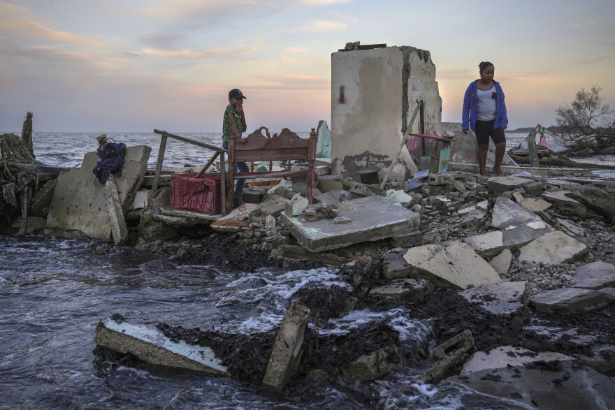 Yahir Mayoral and Emily Camacho walk amid the rubble of their grandmother's home, destroyed by flooding driven by a sea-level rise in their coastal community of El Bosque, in the state of Tabasco, Mexico, Thursday, Nov. 30, 2023. 