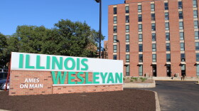 Brick entrance to Illinois Wesleyan University with a row of bushes in front of a sign