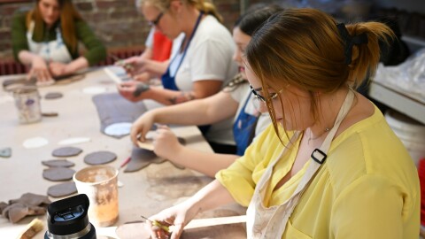 A woman works with a slab of clay during a pottery class