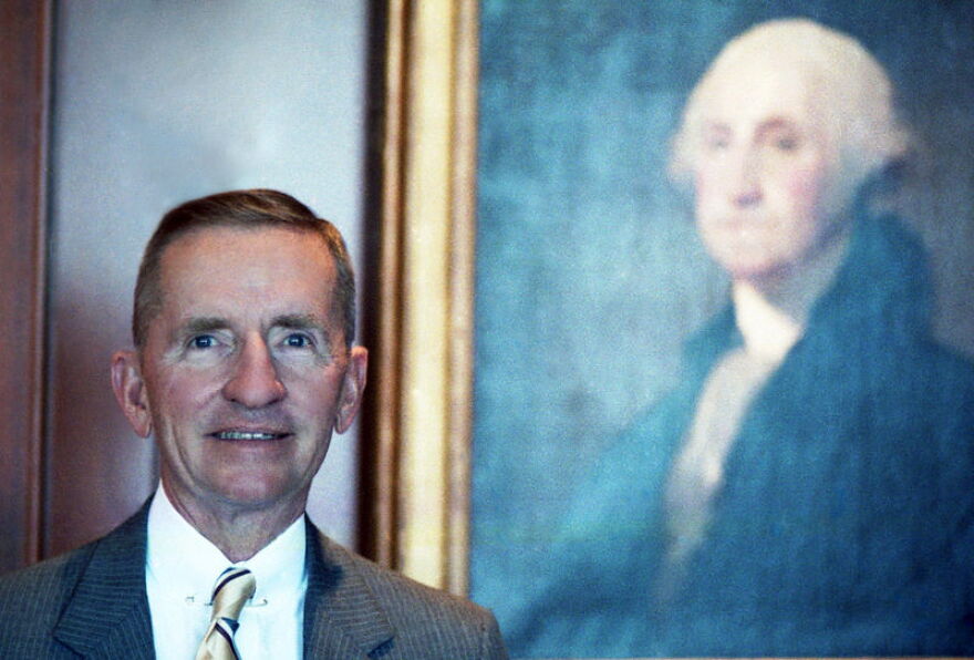 Colour portrait of Ross Perot posing in his office with George Washington painting