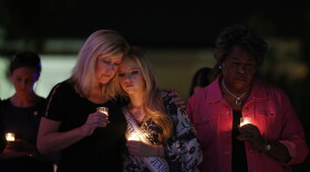Woman hold lit candles at vigil