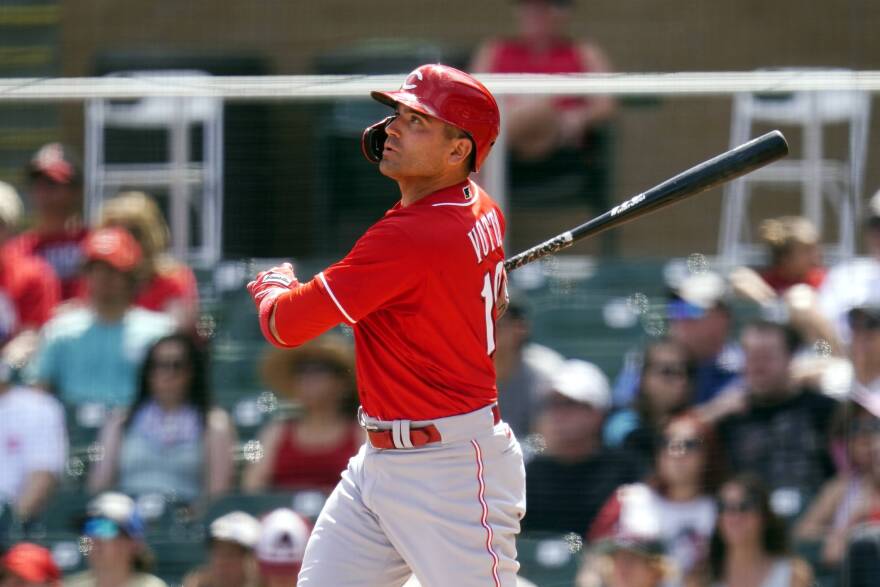 joey votto, in a red baseball jersey and white baseball pants, mid swing