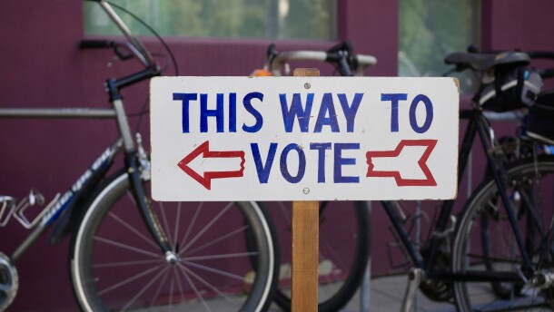 A sign says "This Way To Vote" with bicycles behind it