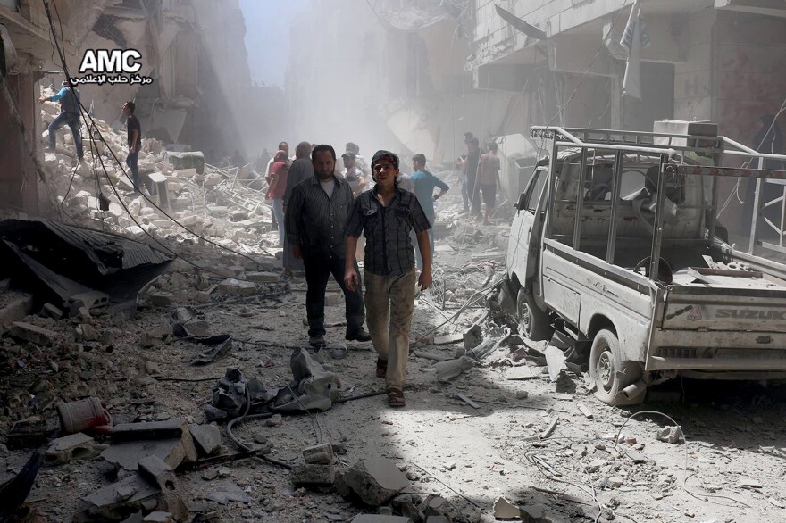 Syrian citizens inspect damaged buildings after airstrikes hit Aleppo, Syria in July, in a photo provided by the Syrian anti-government activist group Aleppo Media Center (AMC).