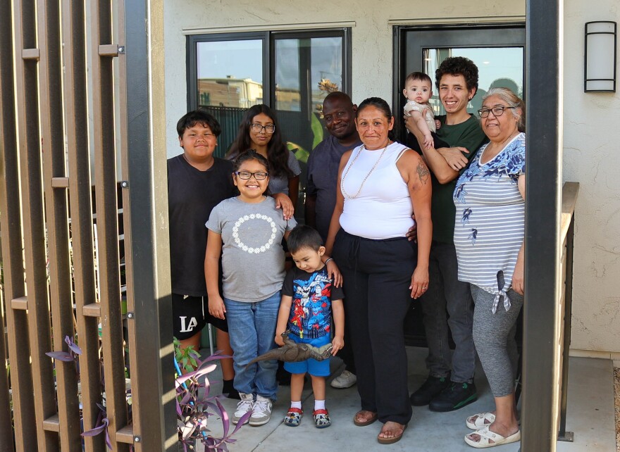Veronica Sanchez, middle, stands at the front door of the apartment provided by Fresno Unified School District, along with her two sons, two daughters, two grandchildren, partner and mother.