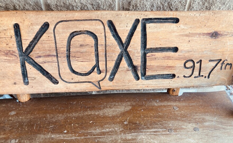 A wooden bench that says "KAXE 91.7fm" on it.