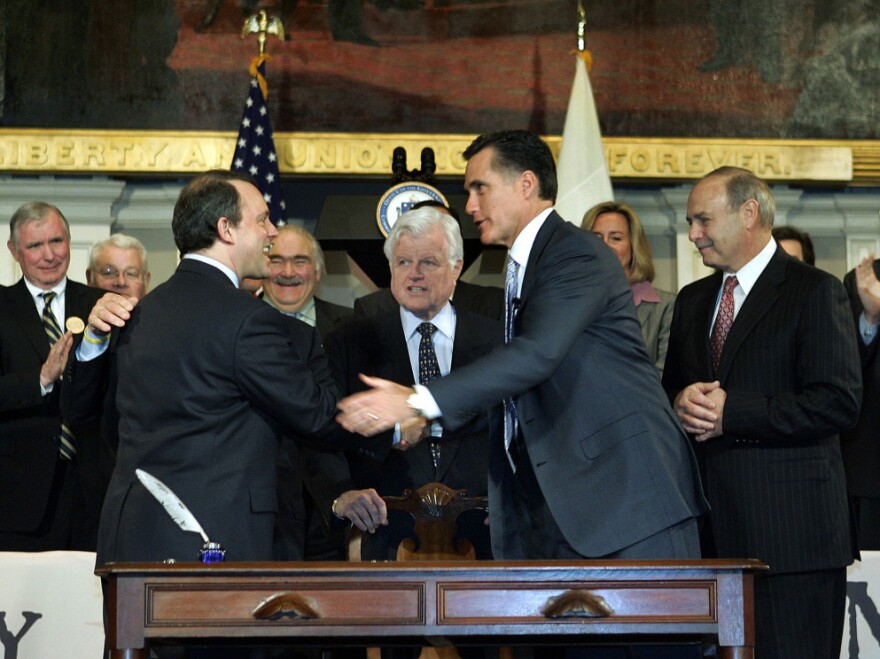 Then-Massachusetts Gov. Mitt Romney shakes hands with Massachusetts Health and Human Services Secretary Timothy Murphy after signing a landmark state health care law on April 12, 2006, in Boston. Sen. Edward Kennedy, D-Mass., stands at center.