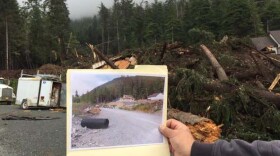 Governor Walker holds up a "before" photo against a a backdrop of damages from the Sitka landslides. Gov. Walker is in Sitka on Aug. 19 surveying the damage. Photo: Governor's office.