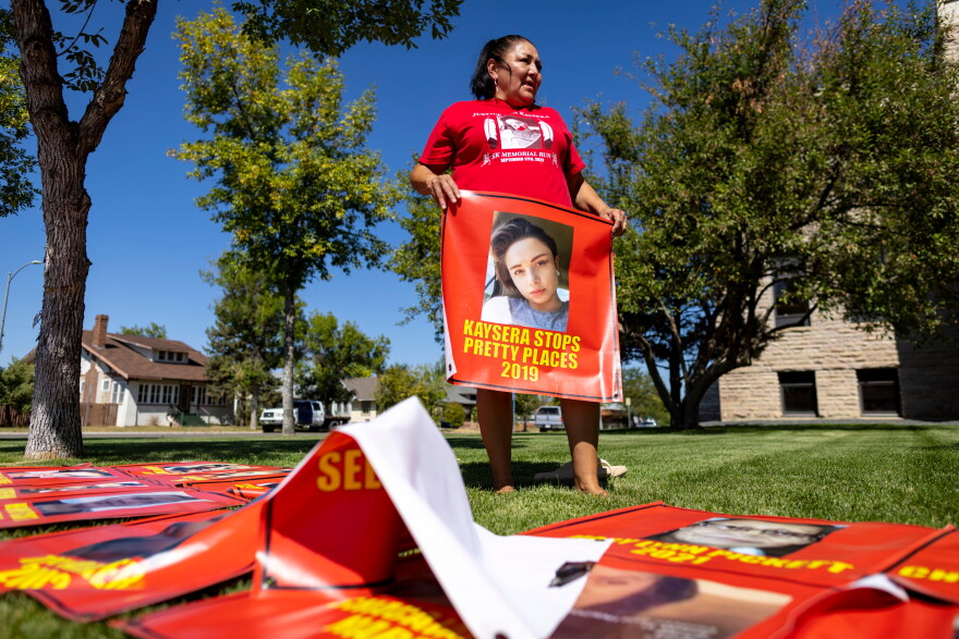 FILE - Melissa Lonebear holds a banner with a picture of Kaysera Stops Pretty Places on it during a rally in support of the Missing and Murdered Indigenous People movement at the Big Horn County Building on Aug. 29, 2023, in Hardin, Mont.