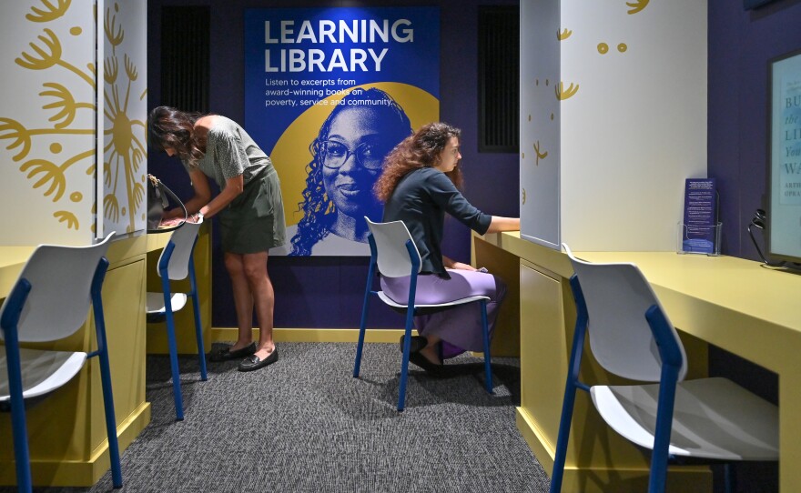 Mary and Abbey Murphy look over the listening library inside the traveling People of Hope Museum. The library features books on hope, poverty and service.