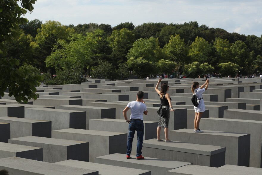 Visitors photograph each other while standing on concrete slabs at the Holocaust Memorial in Berlin in 2016.