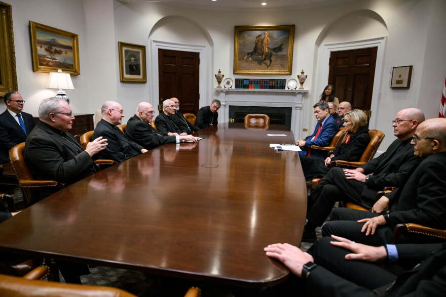 A group of Catholic bishops sit around a conference table with officials from the Trump administration.