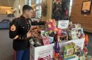 A marine in full uniform looks out over a packed bunch of boxes overflowing with toys.