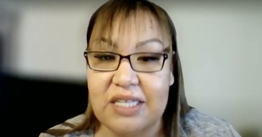 A woman speaks on Zoom with a blurred background.