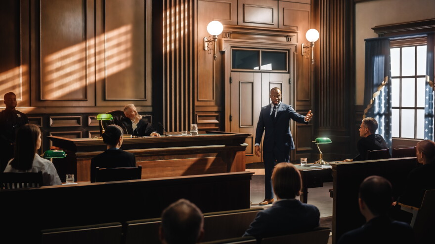 Stock image of a male public defender making a passionate speech to a judge and jury.