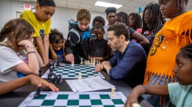Chess grandmaster Gabriel Flom (seated right center) teaches young people how to play chess at the Peeler Recreation Center in Greensboro on July 18. Photograph by Ivan Saul Cutler.