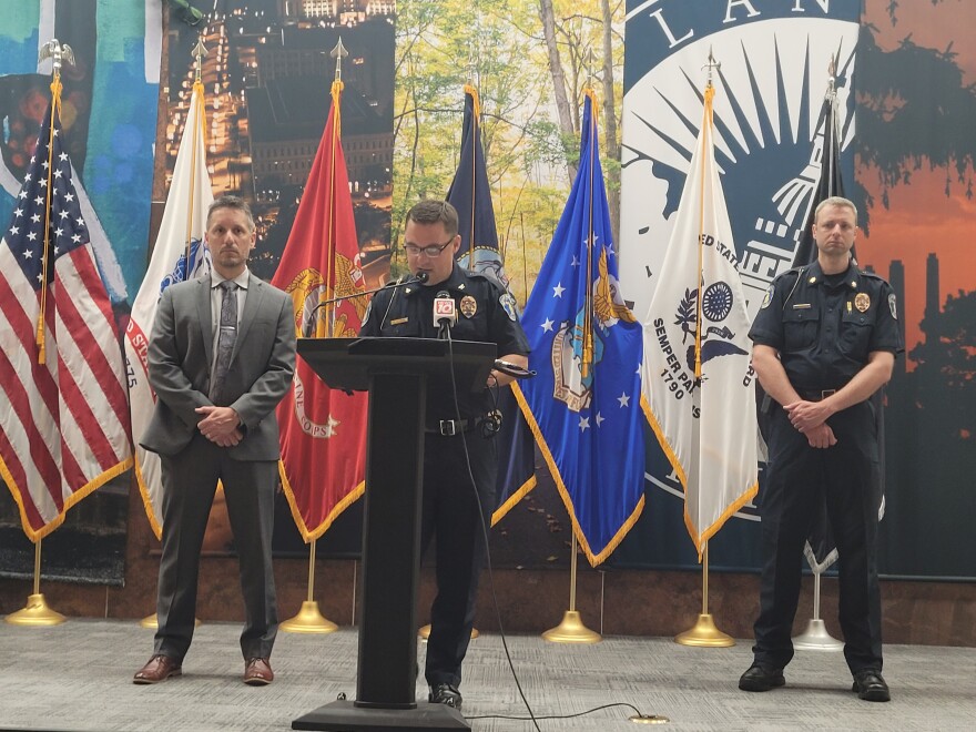  Lansing Police Chief Ellery Sosebee speaks into a micophone on a lectern, on his left is Supervisory Special Resident Agent Mark Civiletto with the FBI and on is right is Assistant Chief Robert Backus