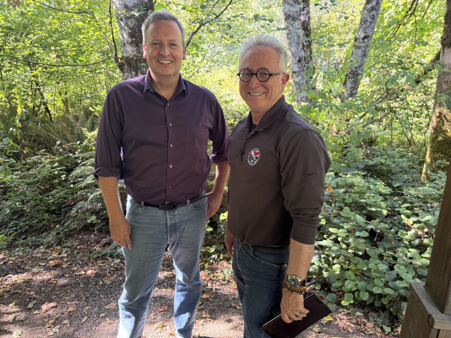 Washington Commissioner of Public Lands Dave Upthegrove (L) and state forester George Geissler stand together smiling amidst trees and greenery in the Capitol State Forest on August 31, 2026.