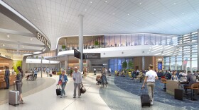 People walking through an airport airside with a second floor that looks over with glass windows. 