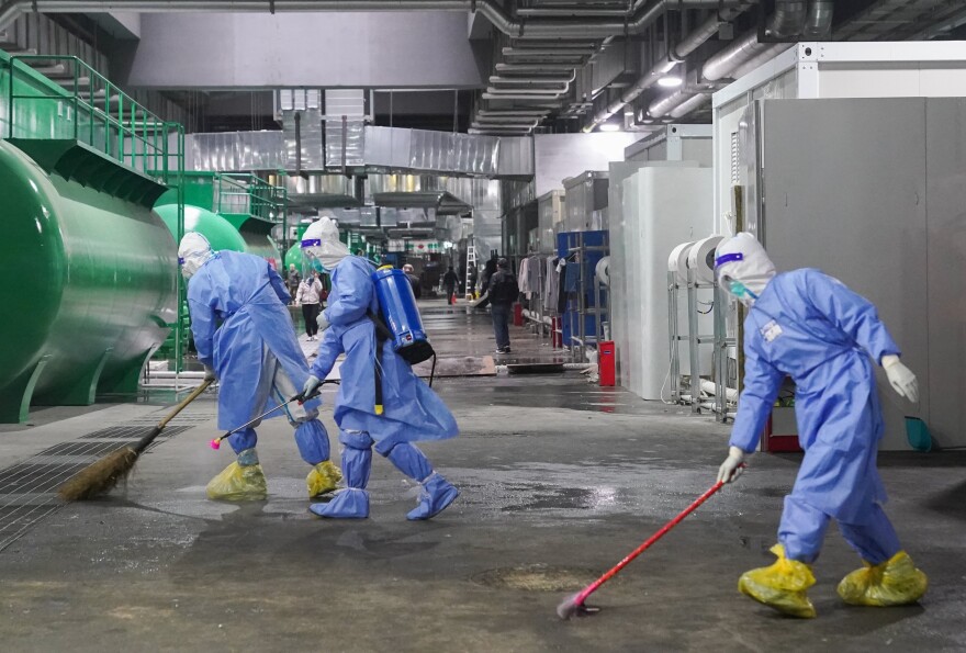 Workers clean and disinfect the floor at the National Exhibition and Convention Center NECC, the largest makeshift hospital, in Shanghai. Many jobs in these temporary facilities are drawn from the pool of unemployed migrant workers.