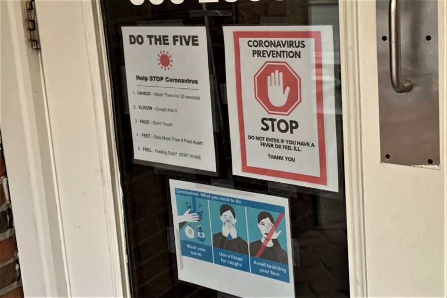 Signs on the door of Village Deli in downtown Bloomington advising customers about COVID-19.
