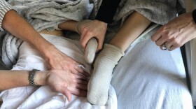 Robyn Adcock (left), a University of California, San Francisco pain relief specialist, gently guides Jessica Greenfield to acupressure points on her son's foot and leg that have helped relieve his chronic pain.