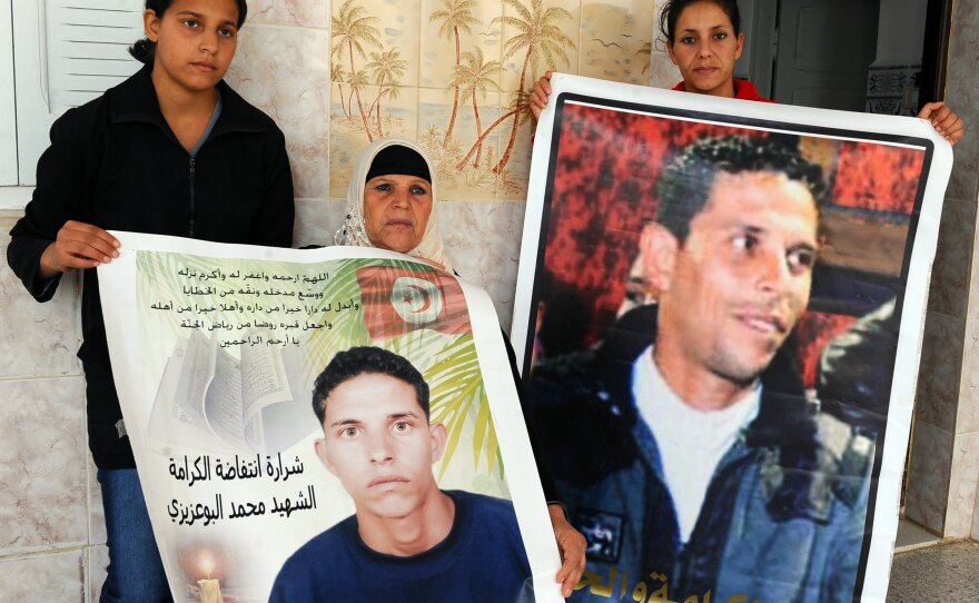 Manoubia Bouazizi (center) holds signs showing her son Mohamed along with her daughters, Basma (left) and Leila, in 2011. Mohamed's self-immolation in December 2010 was part of the impetus to the revolution that later ousted a dictator in Tunisia.