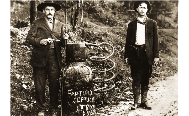 "Law enforcement officers stand beside a captured moonshine still"