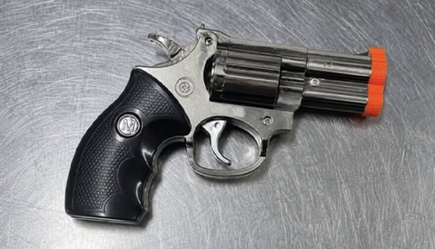 A cigarette lighter that look like a handgun with a black handle and silver barrel.