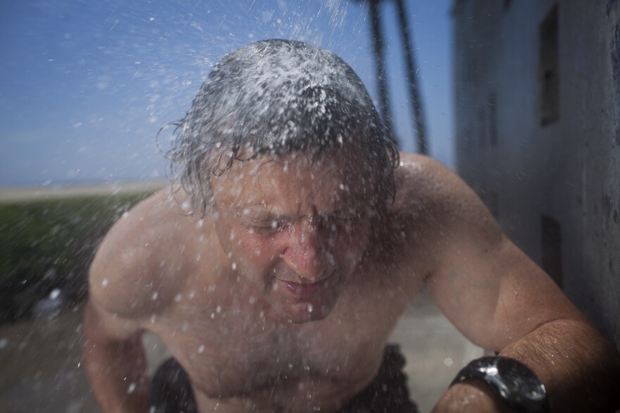 <strong>Shower or meteor shower?</strong> Joe Palca ducks through an outdoor shower in Venice Beach, Calif., to help illustrate how Earth passes through trails of space debris.