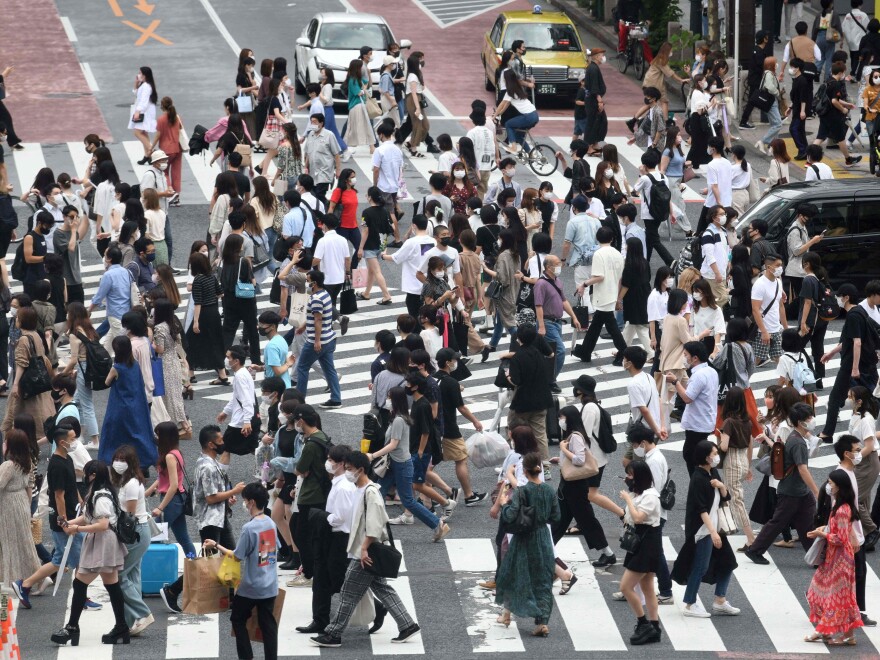 Pedestrians cross the landmark Shibuya Crossing intersection in the shopping and entertainment district of Shibuya in Tokyo on June 27, 2021.