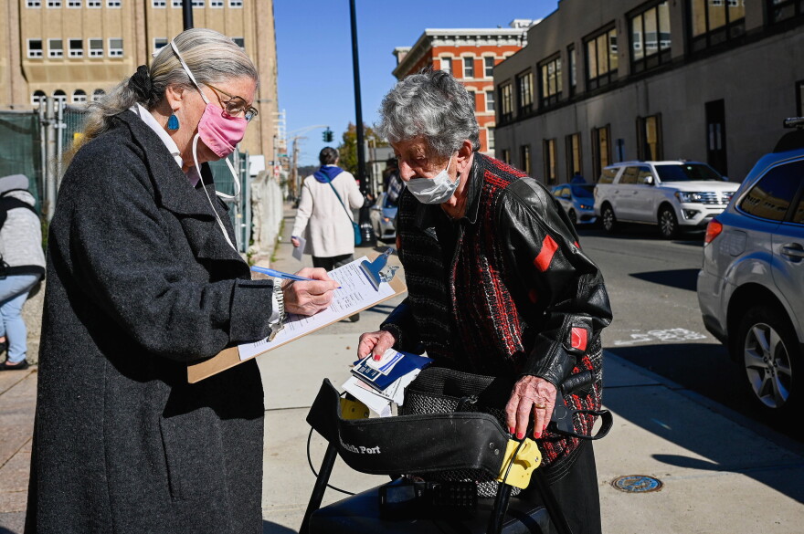 Carol Hollander, left, fills out an application for an absentee ballot for her neighbor and friend, Gertrude Lerman, right. Lerman is 104 years old and made it to the New Haven Hall of Records Saturday so she could cast her ballot.