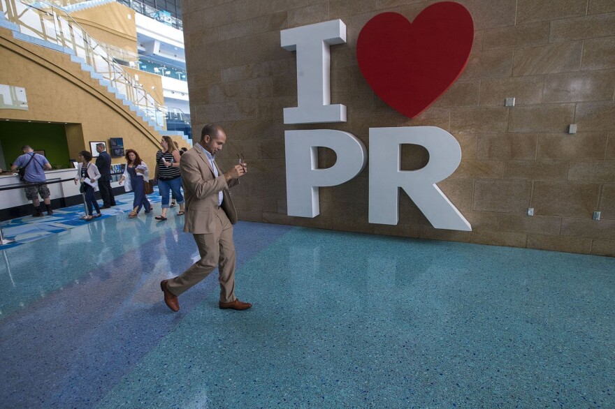 Economist and professor at the University of Puerto Rico  Jose Caraballo Cueto walks past a giant I love Puerto Rico sign in the Puerto Rico Convention Center. (Jesse Costa/WBUR)