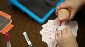 A special educator helps a Cedar Trails Exploration Center student draw.