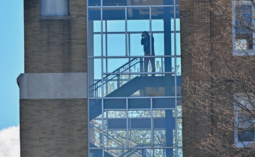 An onlooker takes photos of the state police helicopter's arrival at Misericordia University.