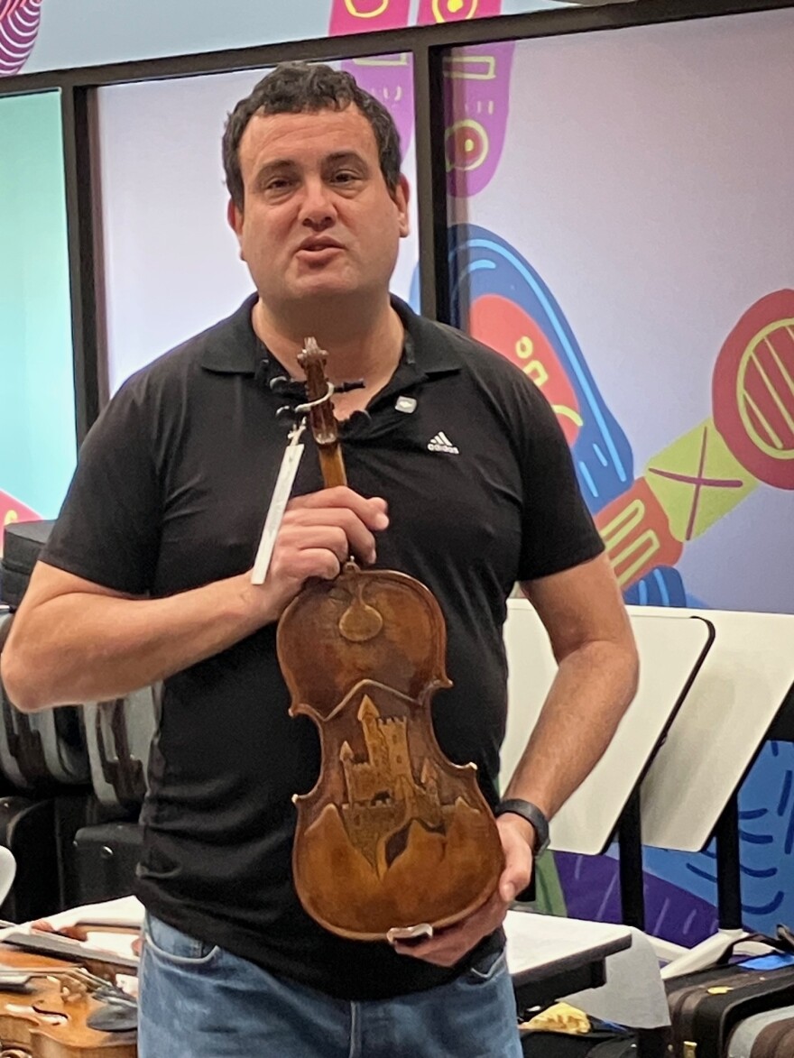 Weinstein holds a carved violin played by a Gypsy during the Holocaust; more than a 1.5 million gypsies were also murdered by the Nazis during World War II.