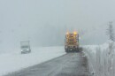 A snowplow clears a few inches of snow off a road