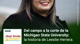 En la imagen se puede observar una fotografia de Leeslie Herrera. Leeslie tiene cabello negro con puntas pintadas rubias. Ella esta usando lentes y una chaqueta y camisa negra. Leeslie tiene los labios pintados de rojo oscuro. Leeslie esta sonriendo en la foto. En el lado inferior de la imagen está el logo de Que Onda Michigan sobre un fondo blanco. En la parte izquiera superior estan las palabras: "WKAR". En la parte derecha las siguientes palabras están escritas: "Del campo a la corte de la Michigan State University: la historia de Leeslie Herrera"  y "Episodio 61". El fondo de la imagen es del color verde. 