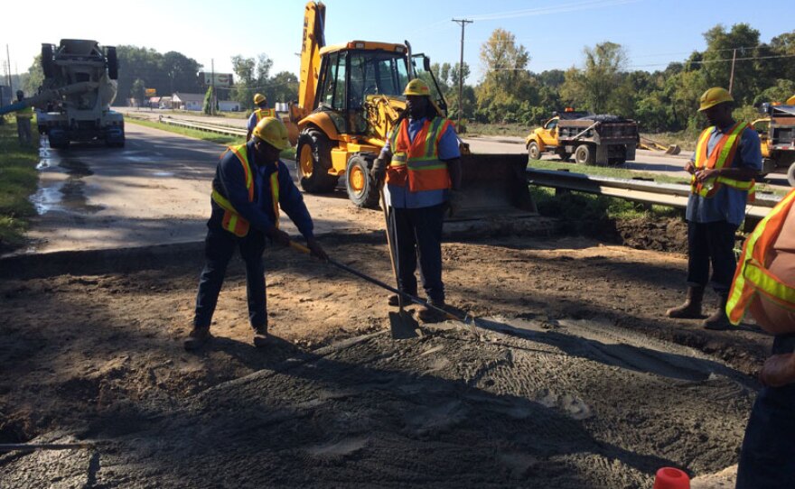 DOT workers fill the washed out bridge approach on Bluff Road at I-77.