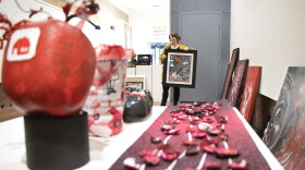 ARTSWIN Gallery Director Andrea Adams holds "Burning My Problems Away" by Lost Akuma, an entrant into the RED exhibit which opens later this month. RED was also an open call exhibit; anyone could apply.