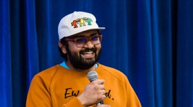 Storyteller Sarthi Manchanda stands and holds a microphone.