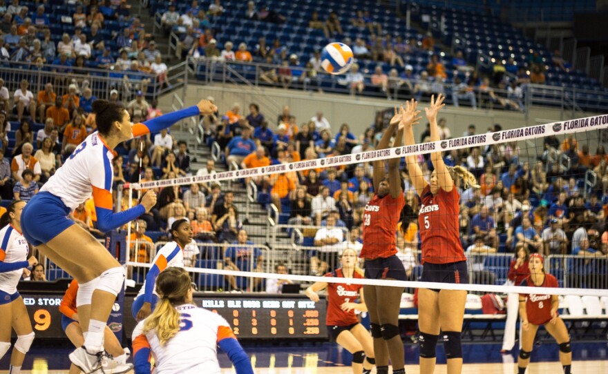 Florida's Alex Holston jumps to spike the ball and score against St. John's.