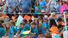 Summer campers at the Loggerhead Marinelife Center wait to see a loggerhead turtle released, waving signs that say "Welcome Home!" and "Good Luck Bovenizer"