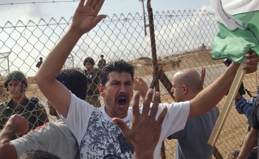 With Israeli soldiers on the other side, Palestinians protest against Israel's West Bank separation barrier in the town of Bil'in in 2008.