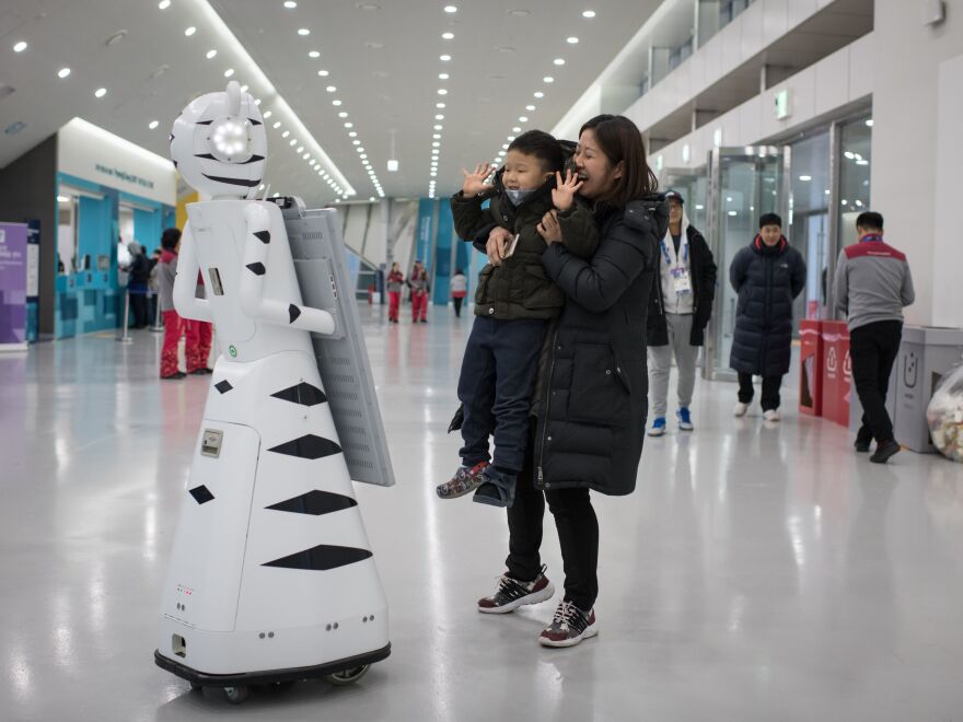 A woman and child pose for a photo before a robot before watching Switzerland and South Korea play ice hockey at the Winter Olympics on Saturday.