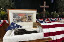 Casket with photos of Sgt. Adolph Aguirre and his uniform. American flag draped over. 