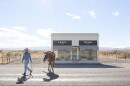 A model leads a horse around Prada Marfa during a photo shoot.