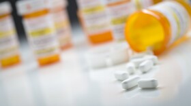 Variety of Medicine Bottles Behind Pills Spilling From Fallen Bottle.