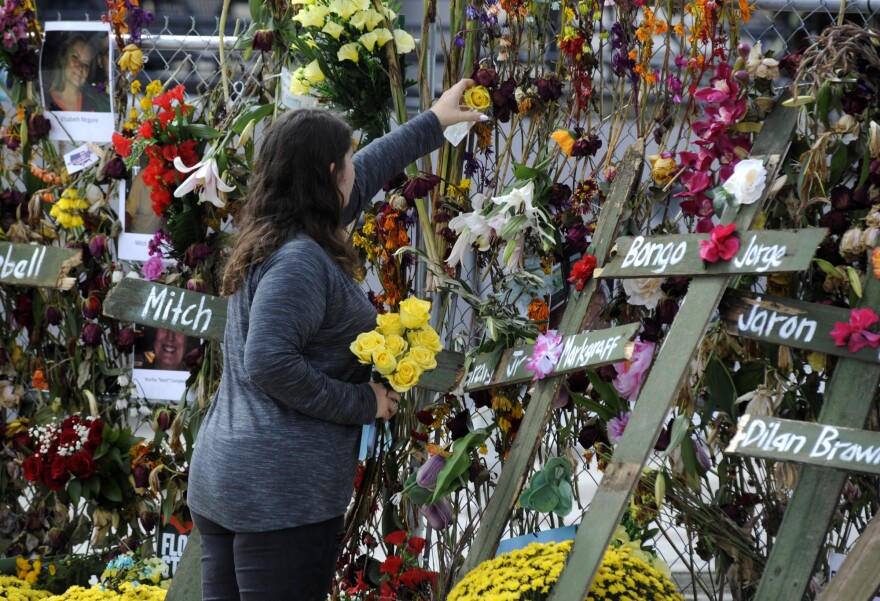 Holly Harmon places a rose into a memorial for victims of Hurricane Ian in Fort Myers, Fla., on Monday, Oct. 10, 2022. More than 100 died during the hurricane, with the greatest number in Lee County.